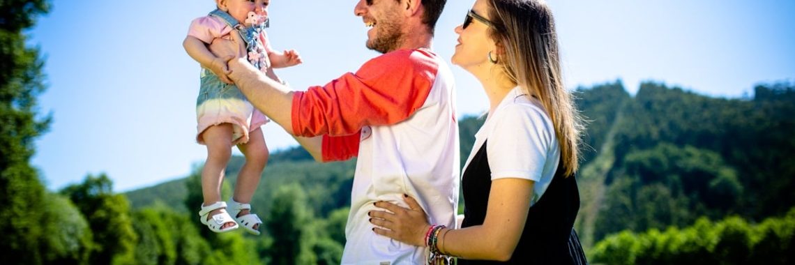 man in white and red polo shirt carrying girl in blue denim jeans during daytime