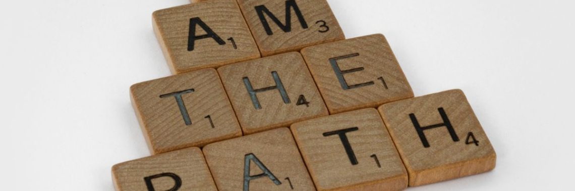 Scrabble tiles arranged to form the quote 'I am the path' on a white surface.