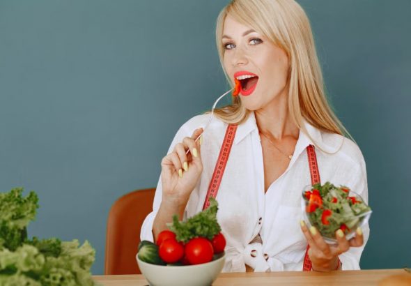 Woman enjoying a fresh salad with tomatoes and greens, promoting healthy eating.