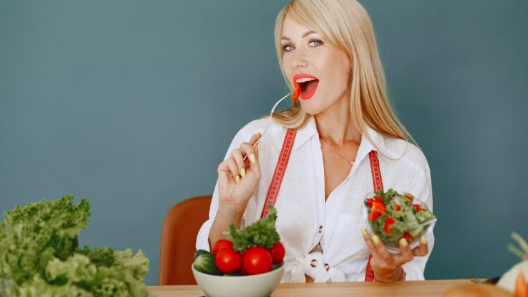 Woman enjoying a fresh salad with tomatoes and greens, promoting healthy eating.