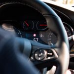 Close-up view of a car dashboard and steering wheel, featuring a digital speedometer display.