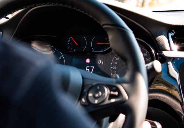 Close-up view of a car dashboard and steering wheel, featuring a digital speedometer display.