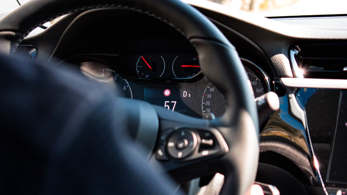 Close-up view of a car dashboard and steering wheel, featuring a digital speedometer display.